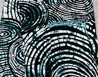 May include: Black and white fabric with a teal blue pattern of concentric circles. The fabric has the text "VERITABLE PRINTED BY AFROCENTRIC" on the bottom edge.