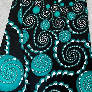 Könnte beinhalten: Schwarzer Stoff mit einem sich wiederholenden Muster aus blaugrünen und weißen Spiralen und Punkten. Der Stoff hat eine glatte Textur.