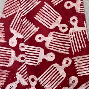 Peut inclure: Tissu rouge avec un motif répétitif de formes blanches en forme de peigne. Le motif présente des figures stylisées, chacune ressemblant à un peigne avec une tête arrondie et des lignes parallèles. Le tissu a un aspect texturé.