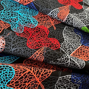 May include: Black fabric with a repeating pattern of orange, red, and blue leaf shapes. The leaves are outlined in black and have a textured, net-like design.