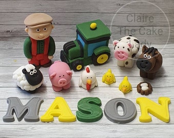 Pode incluir: Conjunto de topo de bolo com tema de fazenda com um trator verde, um fazendeiro, uma ovelha, um porco, uma galinha, dois pintinhos, uma vaca, um cavalo, um ninho com ovos e o nome Mason escrito em letras cinza, amarelas e verdes.