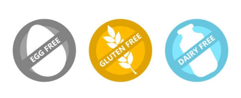 May include: Three round, color-coded icons with a diagonal line through them. The gray icon has a white egg with the text "Egg Free". The yellow icon has a white wheat stalk with the text "Gluten Free". The blue icon has a white milk carton with the text "Dairy Free".