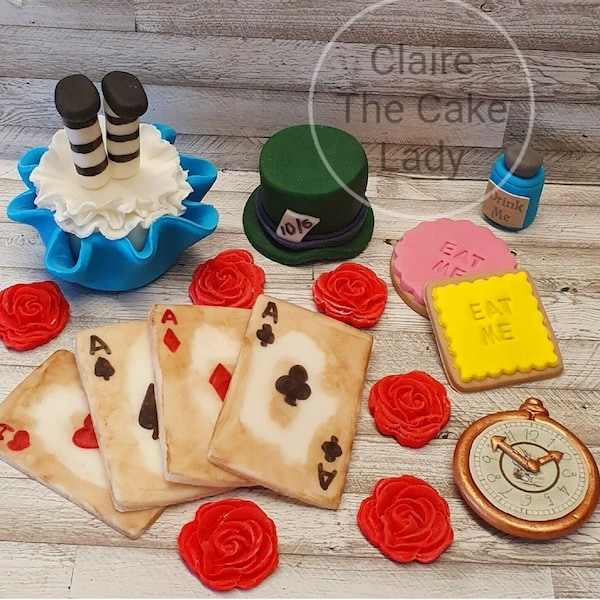 Peut inclure: Accessoires de décoration de gâteau sur le thème d'Alice au pays des merveilles. L'ensemble comprend un cupcake avec des jambes à l'envers, un chapeau haut de forme, quatre cartes à jouer, deux biscuits qui disent "Mange-moi", une bouteille, cinq roses rouges et une montre de poche.