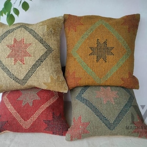 Puede incluir: Cuatro cojines decorativos con un patrón geométrico de estrellas en varios colores, incluyendo rojo, marrón, verde y amarillo. Los cojines están hechos de una tela tejida con una superficie texturizada.