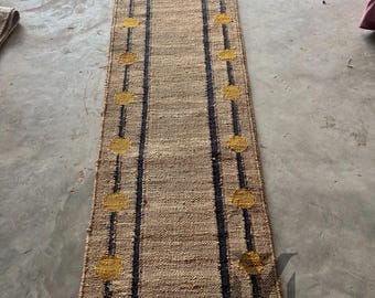 May include: A long, narrow jute rug with a black border and yellow circles. The rug has a simple, modern design.