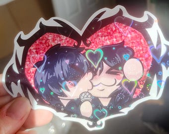 May include: A die-cut sticker featuring a holographic heart-shaped background with a red glitter effect. The illustration depicts two stylized characters with dark hair, one holding a microphone, surrounded by small glowing heart outlines.
