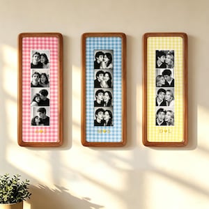 Könnte beinhalten: Drei vertikale Holzrahmen mit Fotostreifen. Der linke Rahmen hat einen rosa Vichy-Karo-Hintergrund, der mittlere einen blauen und der rechte einen gelben. Jeder Streifen zeigt vier Schwarz-Weiß-Fotos mit Initialen und einem Herz.