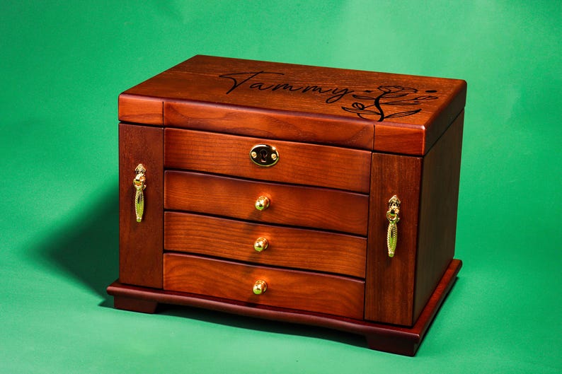 May include: A wooden jewelry box with four drawers and a floral design on the top. The box is labeled "Tammy".