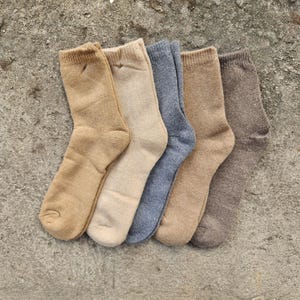 Può includere: Cinque paia di calzini in varie tonalità di marrone e grigio. I calzini sono realizzati in un materiale morbido e confortevole e sono perfetti per l'uso quotidiano.