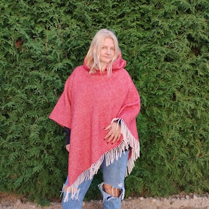 May include: A red and white patterned poncho with a hood and fringe. The poncho is made of a soft, warm material and is perfect for layering in the colder months.