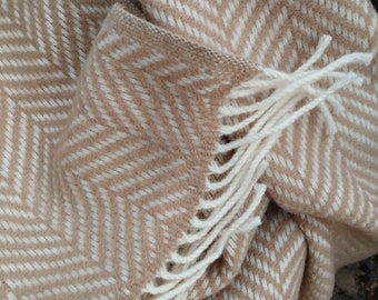 May include: A brown and white chevron patterned throw blanket with fringe. The blanket is made of a soft, fuzzy material.