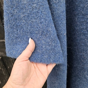 K&ouml;nnte beinhalten: Nahaufnahme eines strukturierten, blauen Stoffes. Der Stoff hat ein leicht verschwommenes Aussehen und eine mittel-dunkelblaue Farbe. Der Stoff ist gefaltet und zeigt die innere Textur. Das Bild zeigt den Rand des Stoffes.