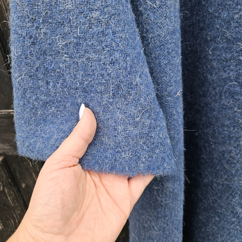 K&ouml;nnte beinhalten: Nahaufnahme eines strukturierten, blauen Stoffes. Der Stoff hat ein leicht verschwommenes Aussehen und eine mittel-dunkelblaue Farbe. Der Stoff ist gefaltet und zeigt die innere Textur. Das Bild zeigt den Rand des Stoffes.