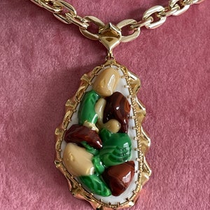 Peut inclure: Un collier en chaîne dorée avec un pendentif composé d'un groupe de pierres vertes, brunes et beiges serties dans un cadre doré.