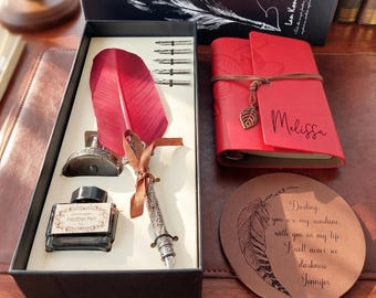 May include: A calligraphy set with a red feather pen, ink bottle, and nibs, presented in a black box. Includes a red journal with "Melissa" inscribed, and a leather coaster with a feather design and text.