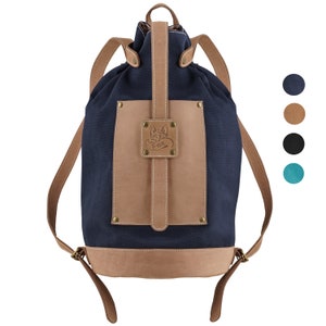 Könnte beinhalten: Ein dunkelblauer Canvas-Rucksack mit einer braunen Lederklappe und einem Fuchs-Logo. Der Rucksack hat einen Kordelverschluss und verstellbare Träger.