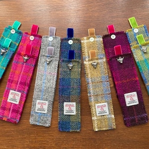 May include: Ten colourful fabric bookmarks with a small silver charm attached to each. The bookmarks are made of a tweed-like fabric and have a contrasting ribbon at the top. The charms are all the same design, a small silver bull's head.