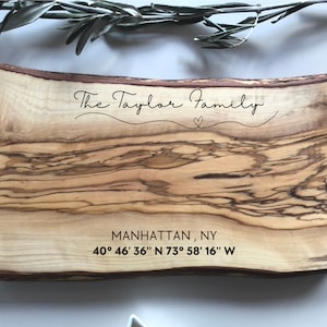 May include: A wooden serving tray with a natural wood grain finish. The tray is engraved with the text "The Taylor Family" and the coordinates "40° 46' 36" N 73° 58' 16" W" along with a small heart symbol.