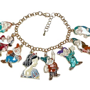 May include: Gold charm bracelet with enamel Snow White and Seven Dwarfs charms. The colourful charms have detailed designs, and the bracelet has a lobster clasp. A whimsical accessory for fans of the classic fairytale.