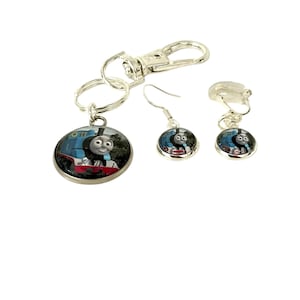 May include: A white ceramic mug with a black handle and the text "But First, Coffee" in a bold, black font. The mug is set against a blurred background, suggesting a cozy setting.