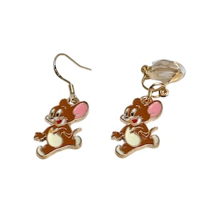 May include: A pair of earrings featuring the cartoon character Jerry. One earring has a hook, the other a clip-on. The earrings are brown with pink ears, white bellies, and gold-colored metal accents.