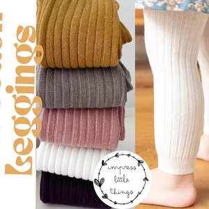 May include: A stack of five ribbed cotton leggings in mustard yellow, gray, dusty pink, white, and dark purple, alongside a pair of white ribbed leggings worn on legs. The text Soft Cotton Leggings and impress little things is visible.