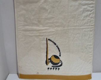 May include: A white cotton tea towel with a yellow and black embroidered design of the New York World's Fair logo. The logo features a stylized depiction of the Trylon and Perisphere, the iconic structures of the 1939-1940 World's Fair.
