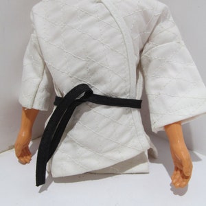 May include: White karate uniform with a black belt. The uniform has a diamond pattern and is made of a soft, lightweight fabric.