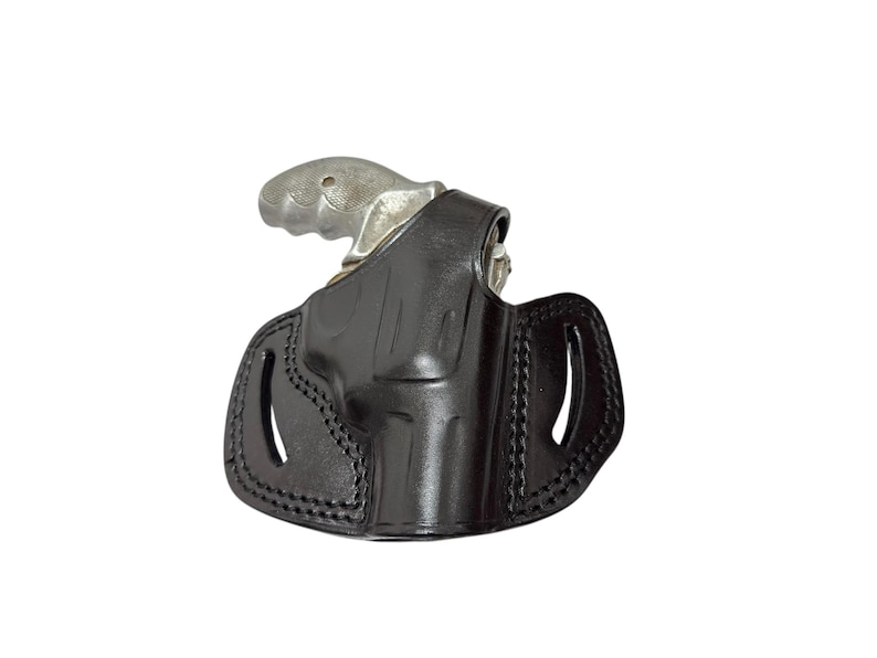 May include: A black leather holster with a silver revolver. The holster has a molded design with stitched edges and two oval cutouts. The revolver's grip is visible above the holster.