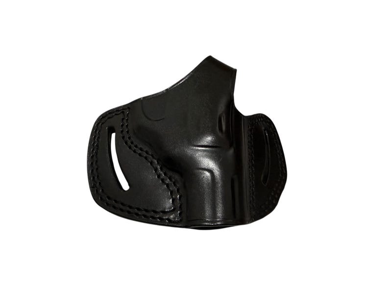 May include: A black leather holster with visible stitching and a curved design. The holster has an open top and a molded shape, likely for a firearm. The leather appears smooth and the overall design is functional.