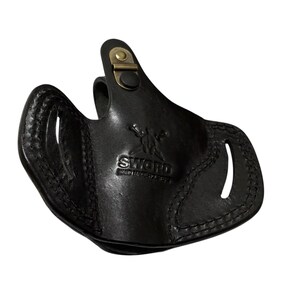 May include: Black leather holster with a stitched design and a brass-colored clasp. The word "SWORD" is embossed on the front. The holster has two openings and a curved shape.