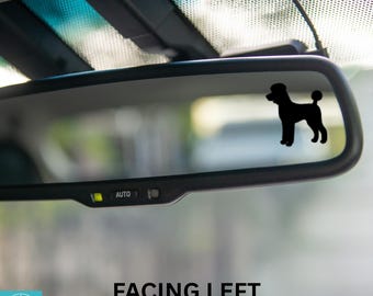 May include: A black silhouette of a poodle facing left is visible in the rearview mirror of a car. The mirror has an "AUTO" button on the bottom.