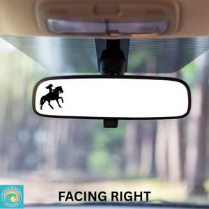 Pu&ograve; includere: Una silhouette nera di una persona a cavallo rivolta a destra, &egrave; mostrata su uno specchietto retrovisore in un'auto. Lo specchietto &egrave; appeso al soffitto dell'auto. Lo sfondo &egrave; sfocato e mostra alberi.
