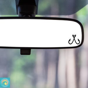 May include: A rearview mirror with a black fishing hook sticker on the glass.