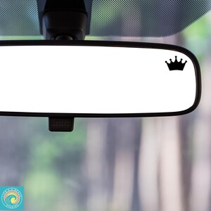 May include: A black crown sticker on a rearview mirror in a car.