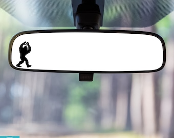 May include: A black silhouette of a Bigfoot facing right is on a rearview mirror in a car. The text "FACING RIGHT" is below the mirror.
