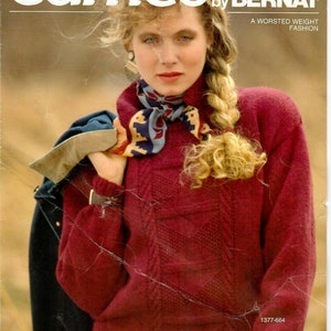 May include: Cover of a vintage fashion magazine titled "Cameo by Bernat." The cover features a woman wearing a burgundy cable-knit sweater, a patterned scarf, and a dark jacket. The magazine promotes "A Worsted Weight Fashion."