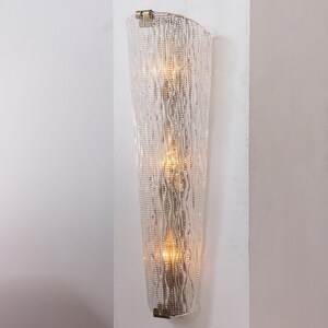 A wall-mounted light fixture with a clear, textured design and two lights embedded within it.