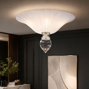 a modern, elegant chandelier with a white, scalloped design hanging from the ceiling in a room with dark walls and a marble-topped table.