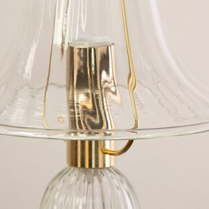 A close-up view of a glass lampshade with a gold-colored metal base, creating a shiny and reflective surface.