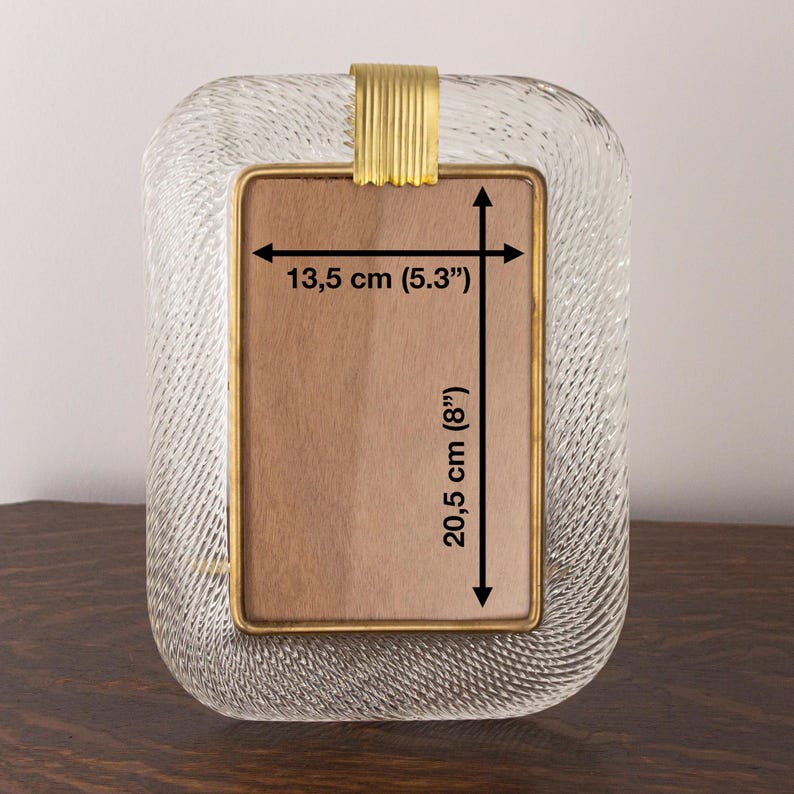 May include: A clear glass picture frame with a gold metal trim. The frame measures 8 inches by 5.3 inches.