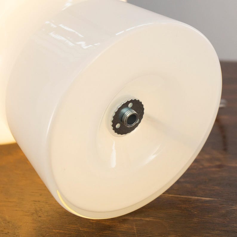 a close-up view of a white lampshade with a metal screw visible through the center.