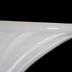 A close-up view of a white, curved surface against a black background.