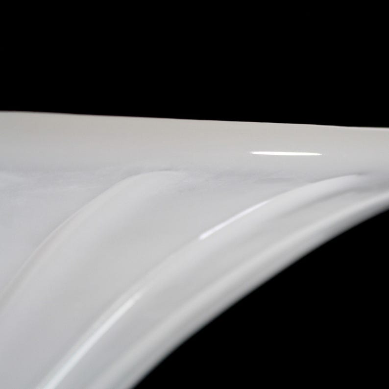 A close-up view of a white, curved surface against a black background.