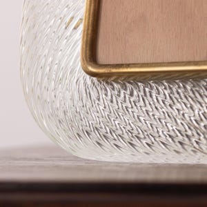 May include: Close-up of a clear glass tray with a textured surface. The tray has a gold-colored metal trim around the edge.
