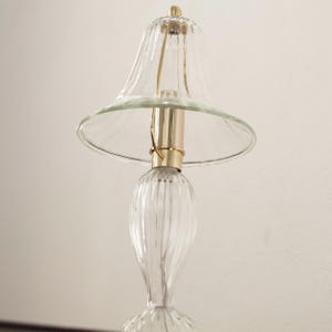 A glass lamp with a clear glass shade and a gold-colored metal base.
