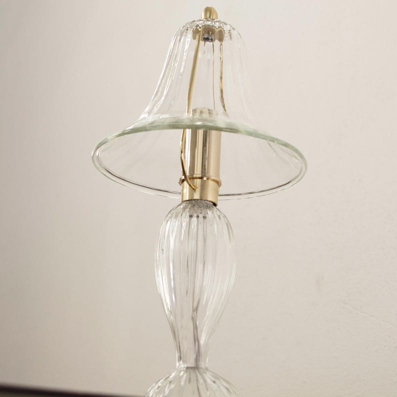 A glass lamp with a clear glass shade and a gold-colored metal base.
