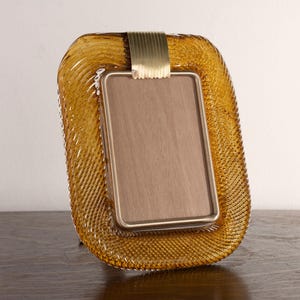 May include: A brown glass picture frame with a gold metal trim. The frame has a textured, wavy design.