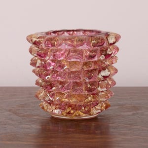 Op de afbeelding: Een kleine glazen houder met een getextureerd, noppenachtig oppervlak. Het glas vertoont een mix van doorschijnend roze en metallic goudkleurige spikkels door de hele structuur, wat zorgt voor een veelzijdige uitstraling met een brede opening.