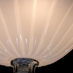 A close-up view of a white, ribbed lamp shade with a metallic base.